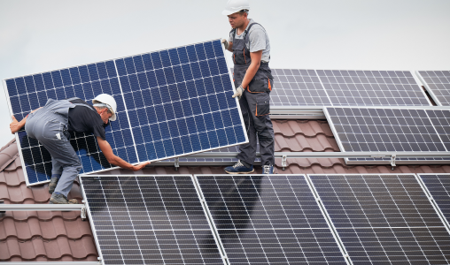 Two installers working on installing solar panels on a residential roof.