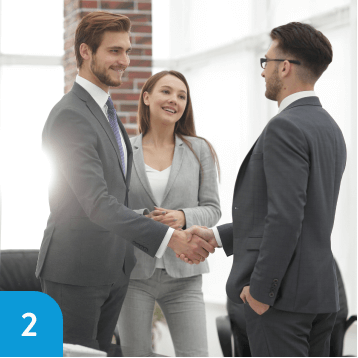 Two men shaking hands in agreement, with a smiling businesswoman witnessing the successful partnership.