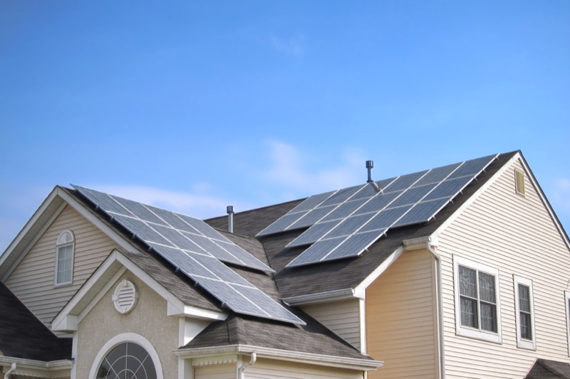 clean green energy saving efficient photovoltaic solar panels on multiple gable suburban house roof over blue sky