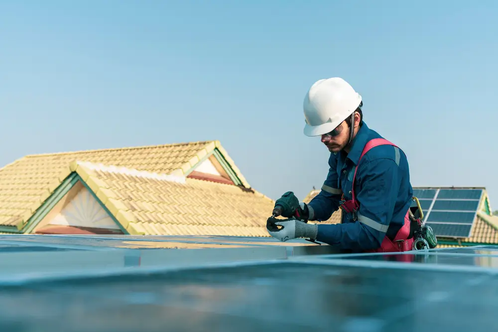 A worker installing the solar panels at roof top of home or home office concept of alternative energy and cost saving for home and small office