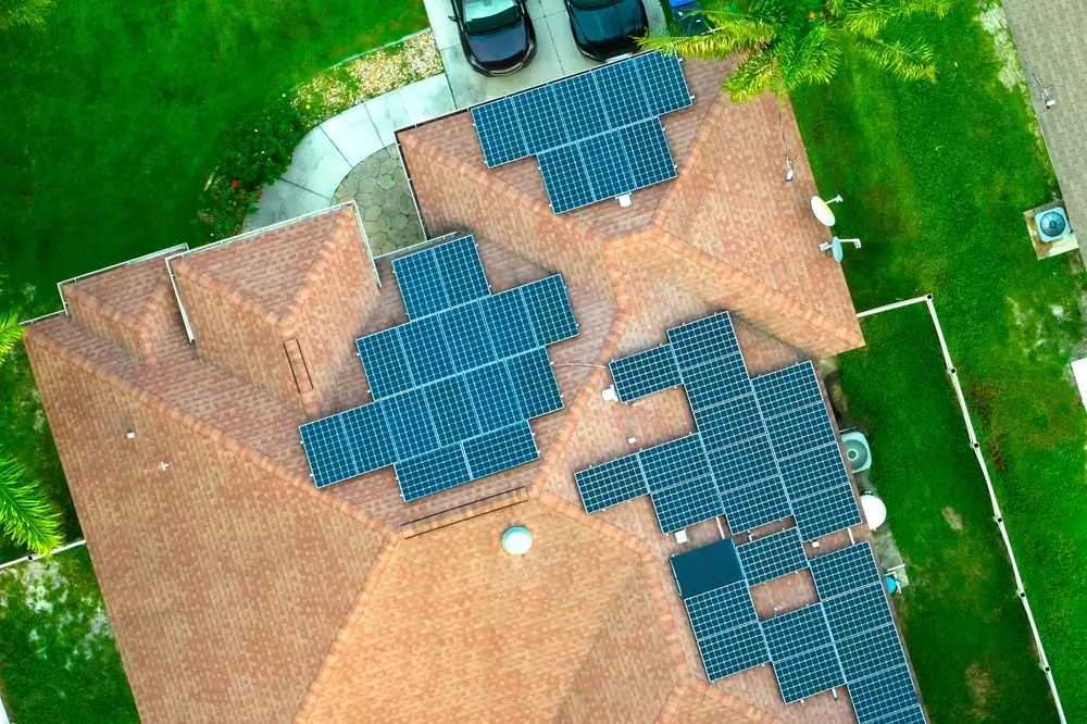 Aerial view of typical american building roof with rows of blue solar photovoltaic panels for producing clean ecological electric energy
